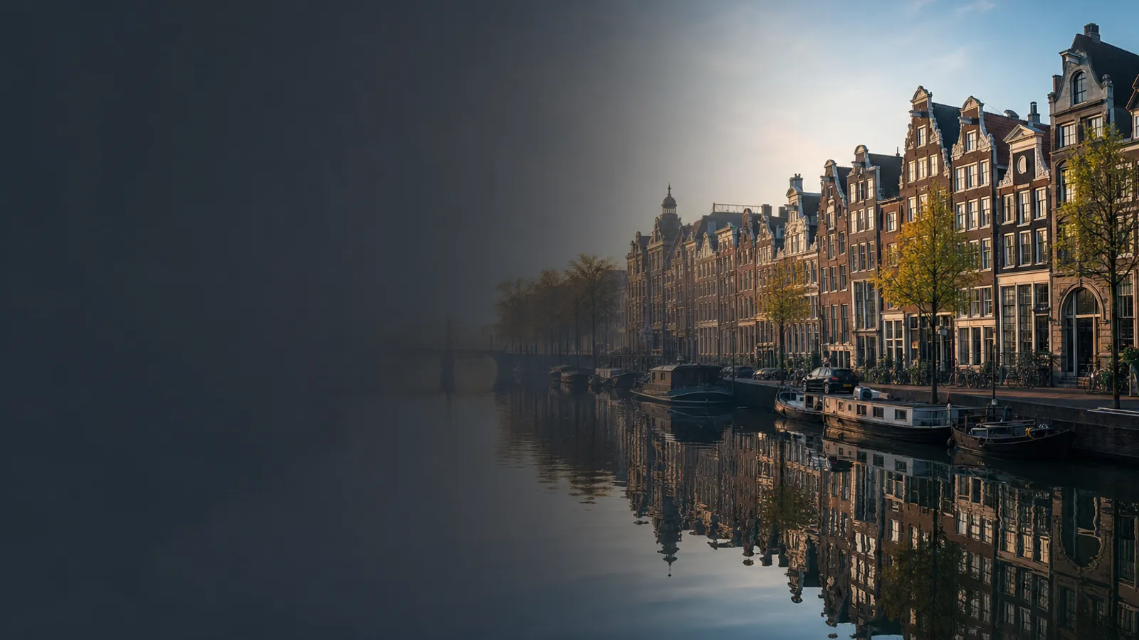 Gabled canal houses reflected in still water with bikes on the bridge